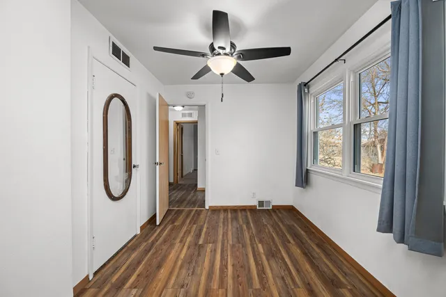 a view of a room with wooden floor fan and windows