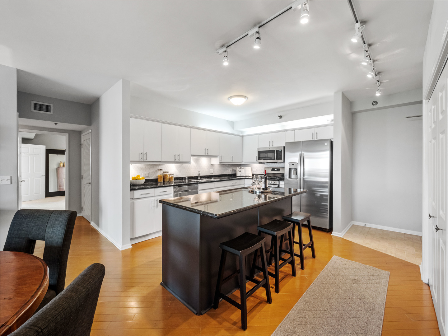 55 West Delaware Place, Unit 921 Chicago, IL 60610 - Photo 10 of 33 a kitchen with stainless steel appliances granite countertop a stove top oven a sink dishwasher a dining table and chairs with wooden floor