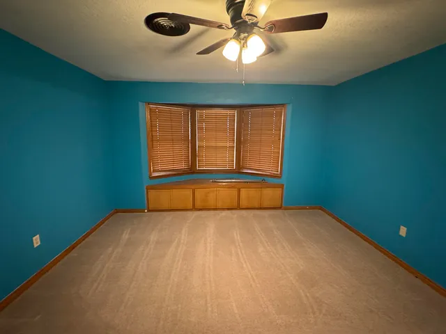 an empty room with a window and a fan