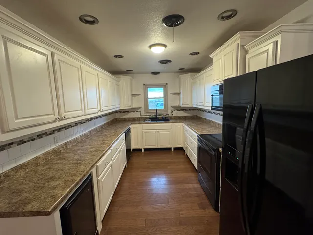 a kitchen with granite countertop a sink and refrigerator
