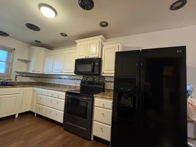 a kitchen with granite countertop white cabinets and black appliances