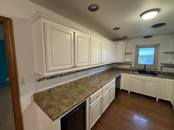 a kitchen with granite countertop a sink and white cabinets
