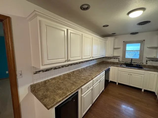 a kitchen with granite countertop a sink and white cabinets