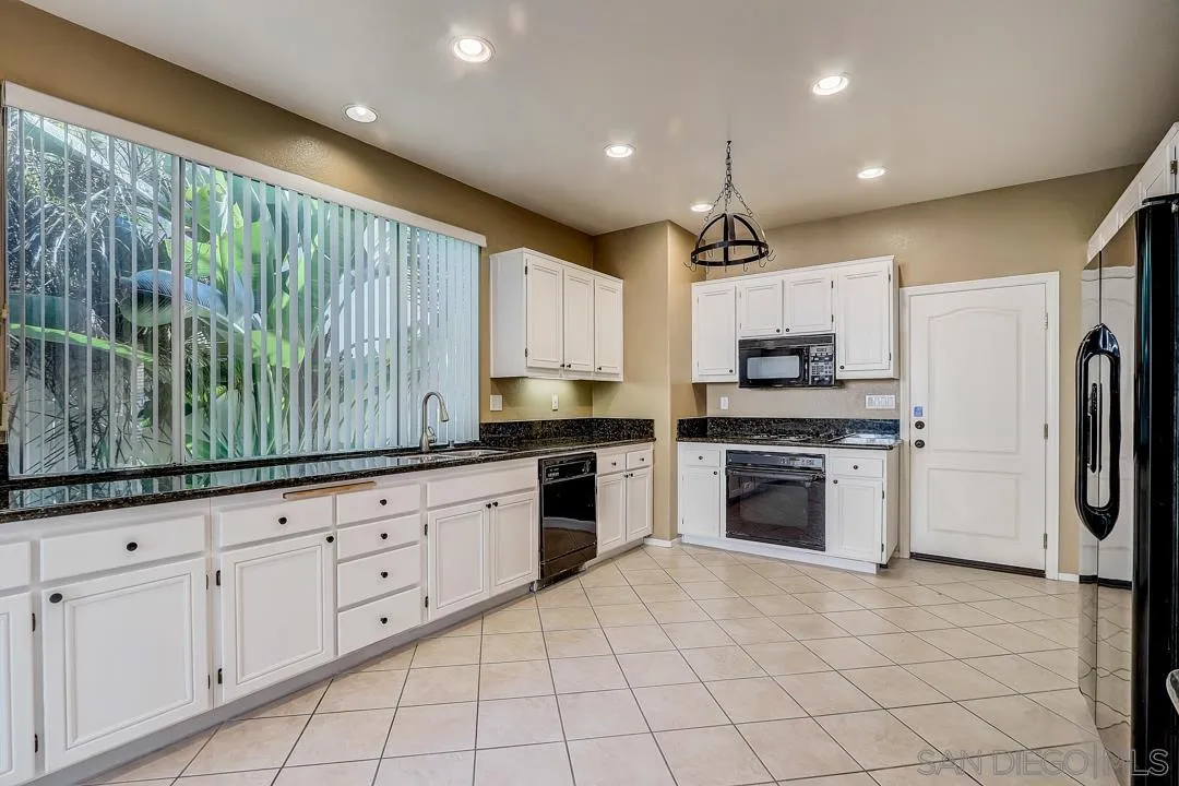 7134 Pintail Drive Carlsbad, CA 92011 - Photo 24 of 30 a kitchen with granite countertop a stove a sink and a refrigerator
