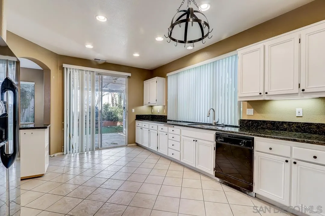 7134 Pintail Drive Carlsbad, CA 92011 - Photo 26 of 30 a kitchen with granite countertop a stove a sink a refrigerator and cabinets