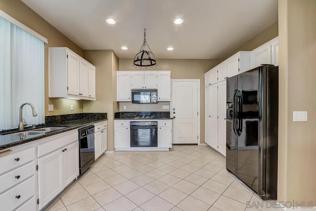 7134 Pintail Drive Carlsbad, CA 92011 - Photo 4 of 30 a kitchen with kitchen island granite countertop appliances cabinets and a sink