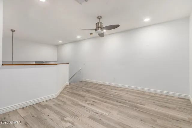 an empty room with wooden floor a ceiling fan white cabinets and wooden floor