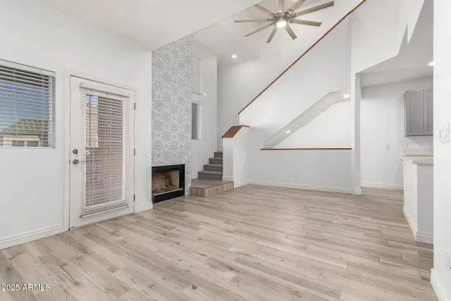 an empty room with wooden floor fireplace and windows