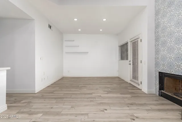 a view of empty room with wooden floor and fireplace