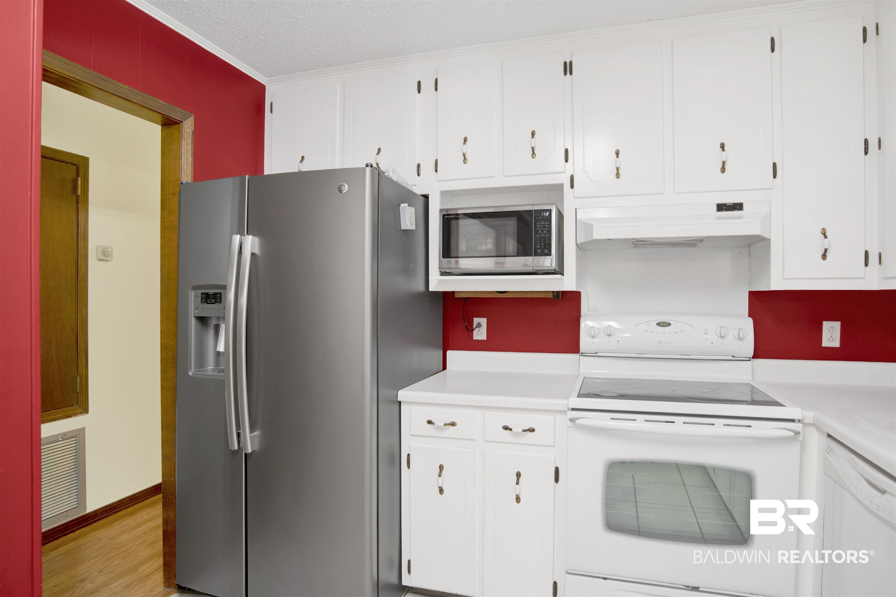 30888 Cemetery Road Daphne, AL 36527 - Photo 13 of 36 Kitchen featuring white upper and lower cabinetry with contrasting red wall panels