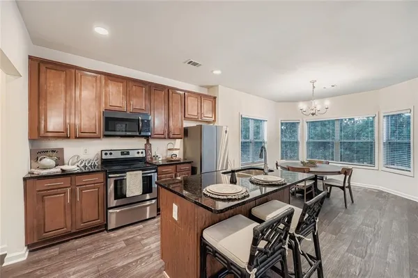 a kitchen with a stove a sink dishwasher a dining table and chairs with wooden floor