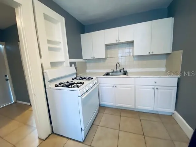 a kitchen with a sink a stove and white cabinets