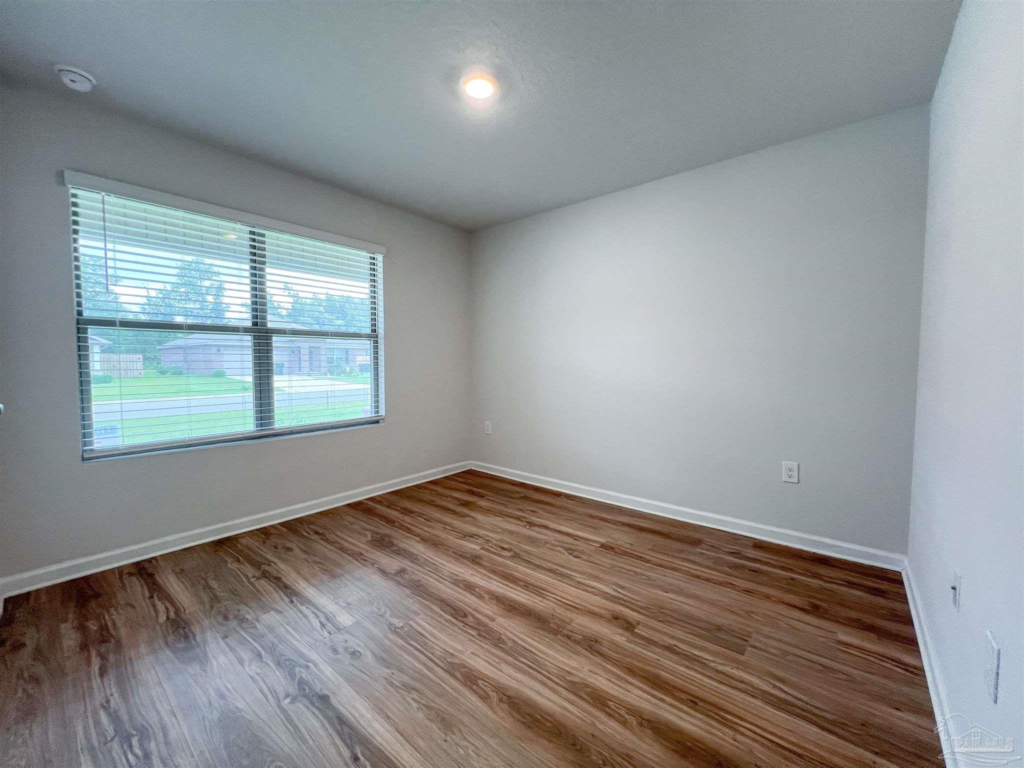 6351 Burrow Lane Pensacola, FL 32526 - Photo 22 of 25 an empty room with wooden floor and windows