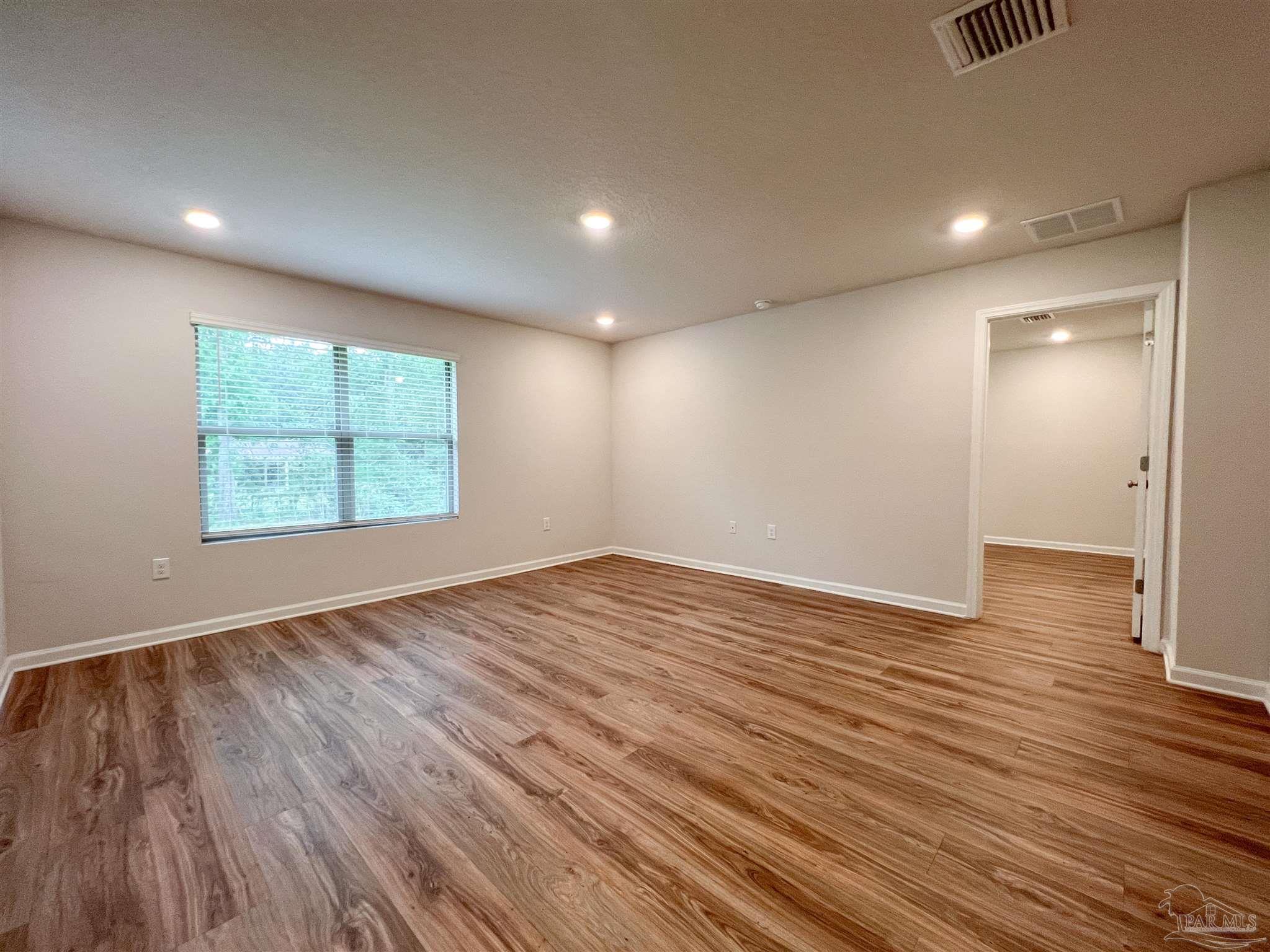6351 Burrow Lane Pensacola, FL 32526 - Photo 4 of 25 an empty room with wooden floor and windows