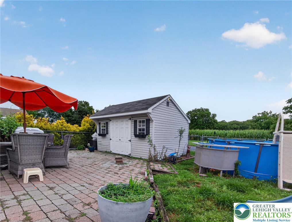 2628 Levans Road Coplay, PA 18037 - Photo 51 of 54 An inviting paved patio with an umbrella offers ample space for outdoor enjoyment beside a practical storage shed.