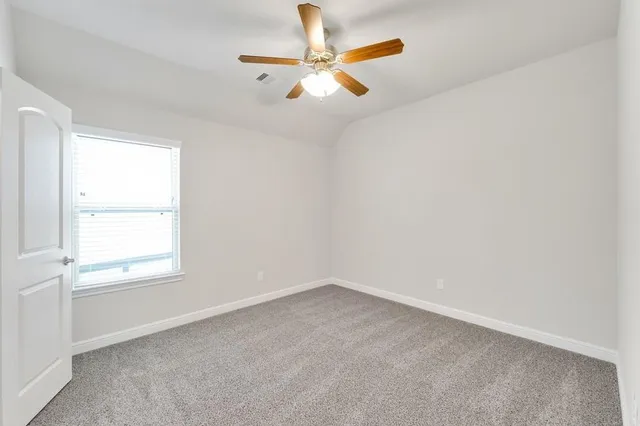 a view of an empty room and window with a ceiling fan