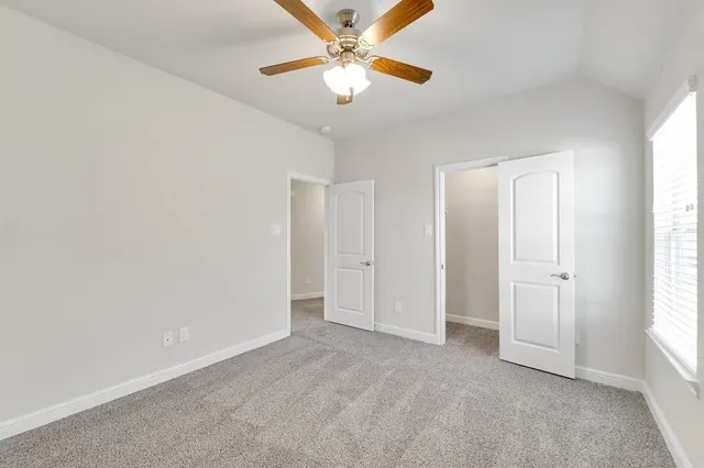 an empty room with a window and a fan