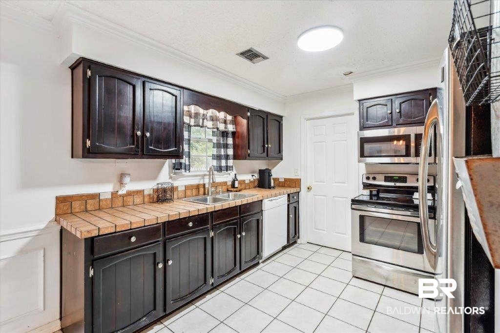 3616 Vista Ridge Drive Mobile, AL 36693 - Photo 5 of 20 Kitchen featuring appliances with stainless steel finishes, sink, ornamental molding, and dark brown cabinetry