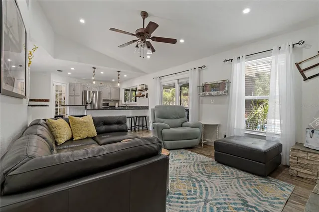 a kitchen with stainless steel appliances granite countertop a refrigerator a sink and white cabinets with wooden floor