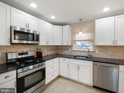 a kitchen with granite countertop white cabinets stainless steel appliances and a sink