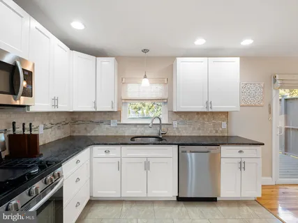 a kitchen with white cabinets stainless steel appliances and sink