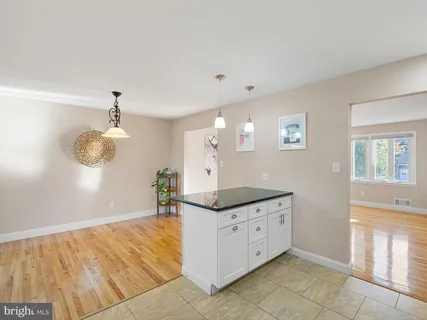 a hallway with granite countertop white cabinets and chandelier