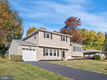 a front view of a house with a garden and tree