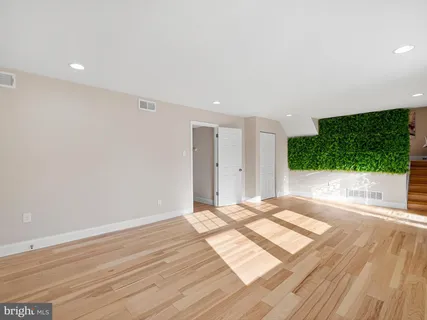 a view of an empty room with wooden floor and windows