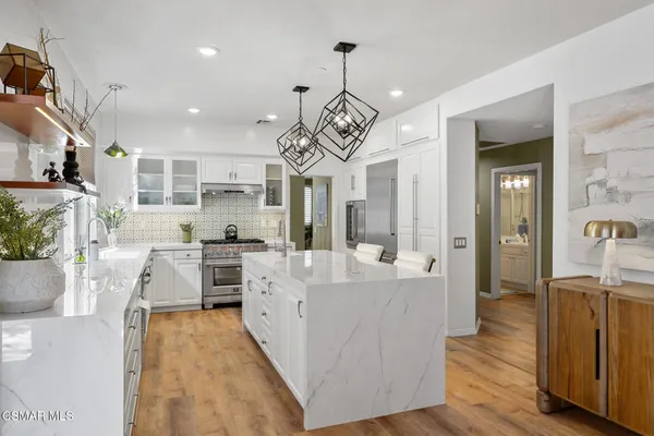 a large kitchen with kitchen island a large counter space a sink stainless steel appliances and cabinets