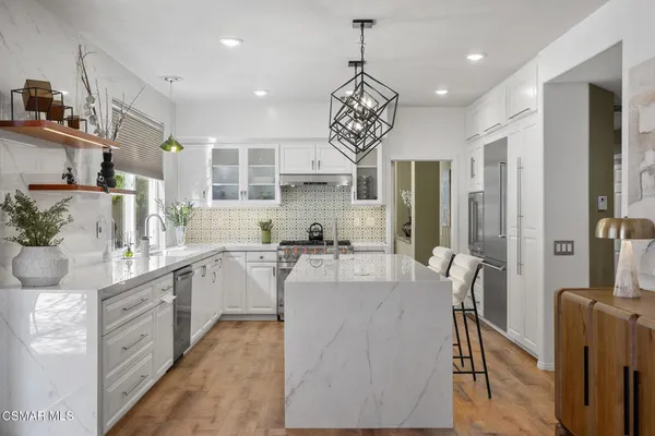 a large kitchen with kitchen island a large counter space a sink stainless steel appliances and cabinets