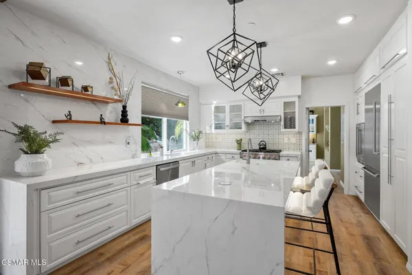 a kitchen with stainless steel appliances kitchen island granite countertop a table chairs in it and wooden floors