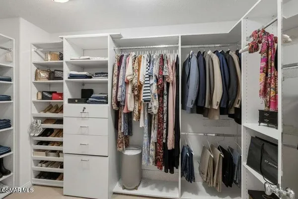a view of walk in closet with clothes and shoes