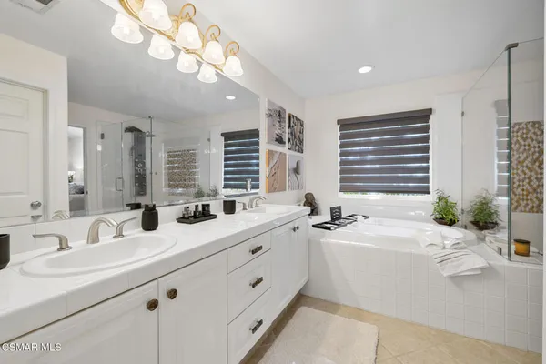 a bathroom with double vanity sinks a vanity a lamp and a bathtub