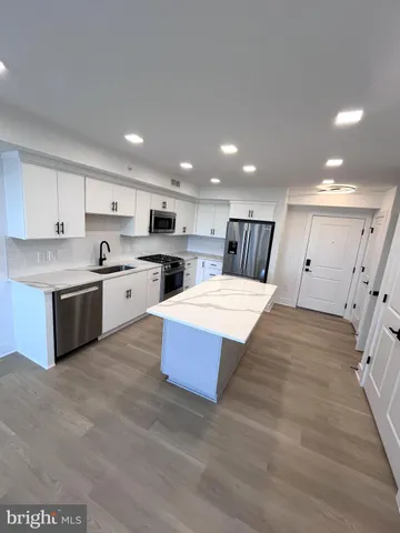 a large kitchen with a large counter top stainless steel appliances and cabinets