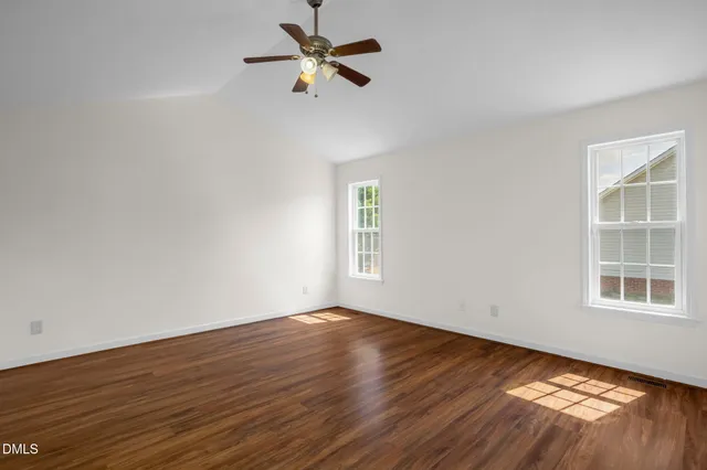 a view of empty room with wooden floor and fan