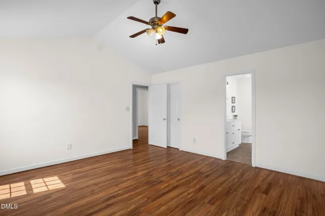 an empty room with wooden floor and fan