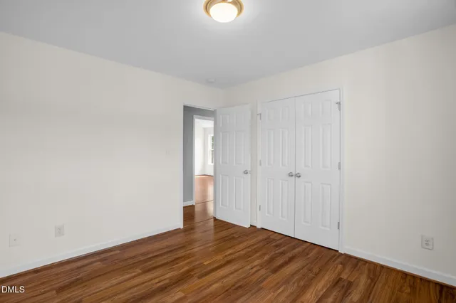 a view of an empty room with wooden floor and windows