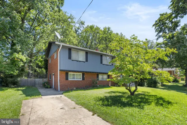 a brick house with a yard plants and large tree