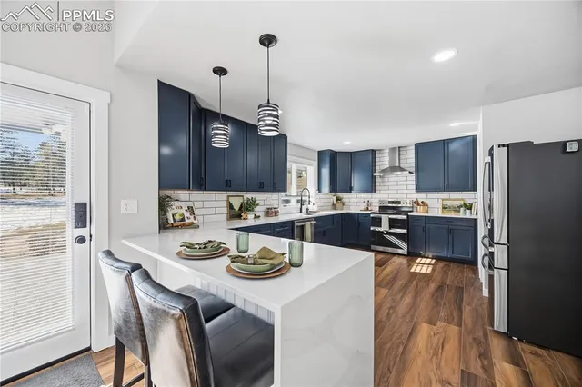 a kitchen with a dining table chairs refrigerator and wooden floor