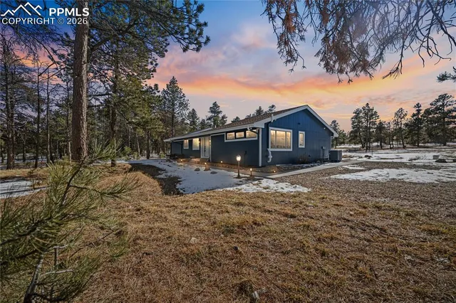 a view of house with yard and trees in the background