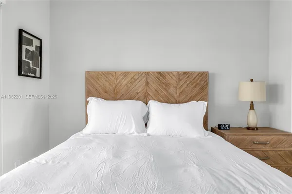 a large bed sitting in a bedroom with a white comforter and pillows