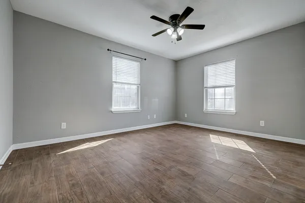 a view of an empty room with window and a chandelier fan