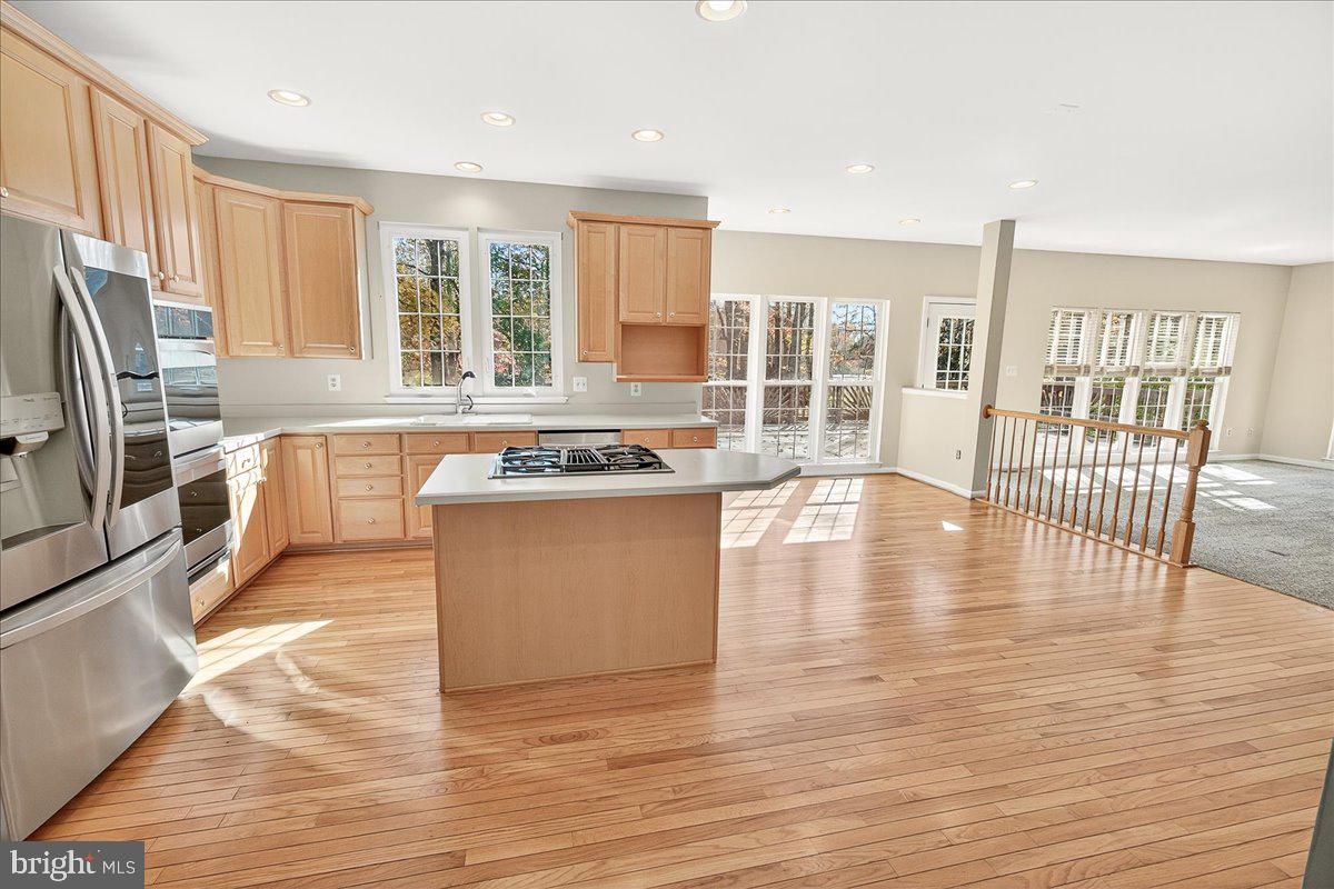 19332 Cissel Manor Drive Poolesville, MD 20837 - Photo 29 of 81 a large kitchen with stainless steel appliances granite countertop a stove top oven a sink dishwasher a dining table and chairs with wooden floor