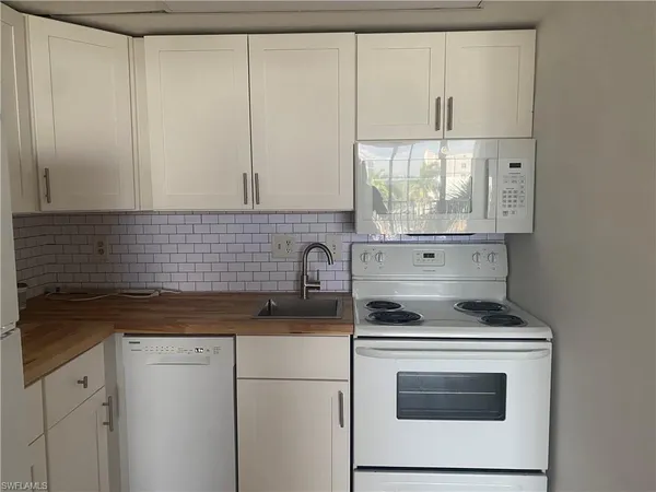 a kitchen with granite countertop white cabinets and white appliances