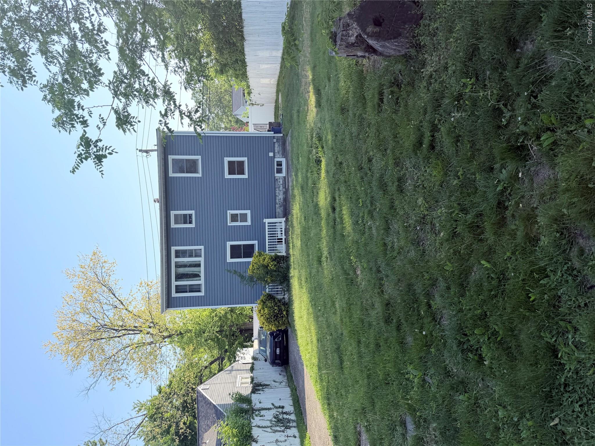 43 Bethpage Road Copiague, NY 11726 - Photo 2 of 3 Exterior showcasing blue horizontal siding, white trim windows, and a white picket fence