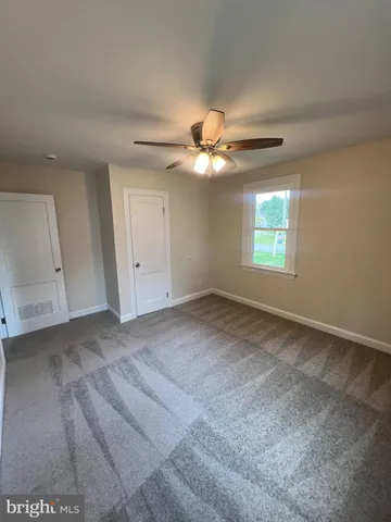 an empty room with a ceiling fan and a window