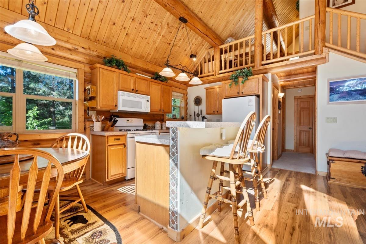 10 Elk Point Road Garden Valley, ID 83622 - Photo 15 of 42 Kitchen featuring light countertops, white appliances, light wood finished floors, a kitchen bar, and a high wood beamed ceiling
