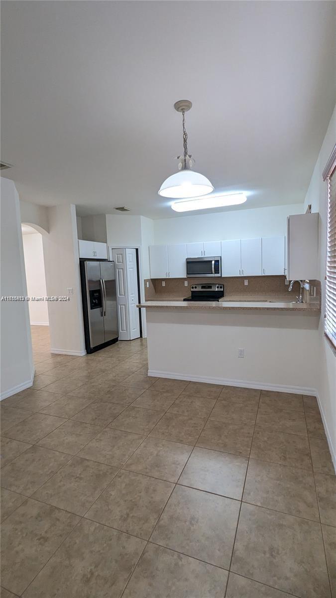 11840 Southwest 154th Avenue, Unit 11840 Miami, FL 33196 - Photo 21 of 61 a kitchen with kitchen island granite countertop a stove top oven a sink a counter space and cabinets
