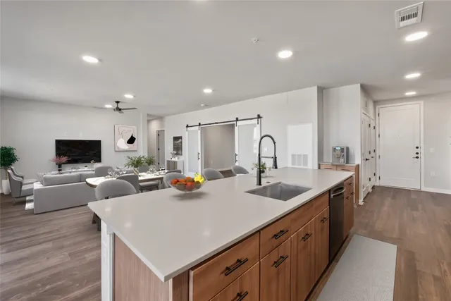 a large kitchen with a large counter top a sink stainless steel appliances and cabinets