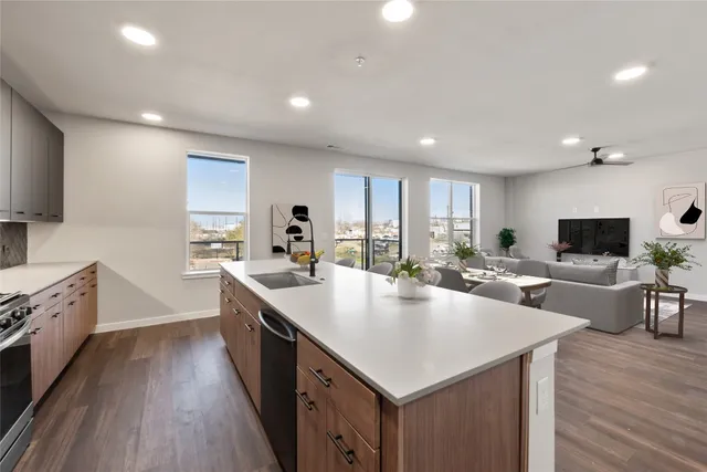 a large kitchen with stainless steel appliances a sink dishwasher stove and wooden floor